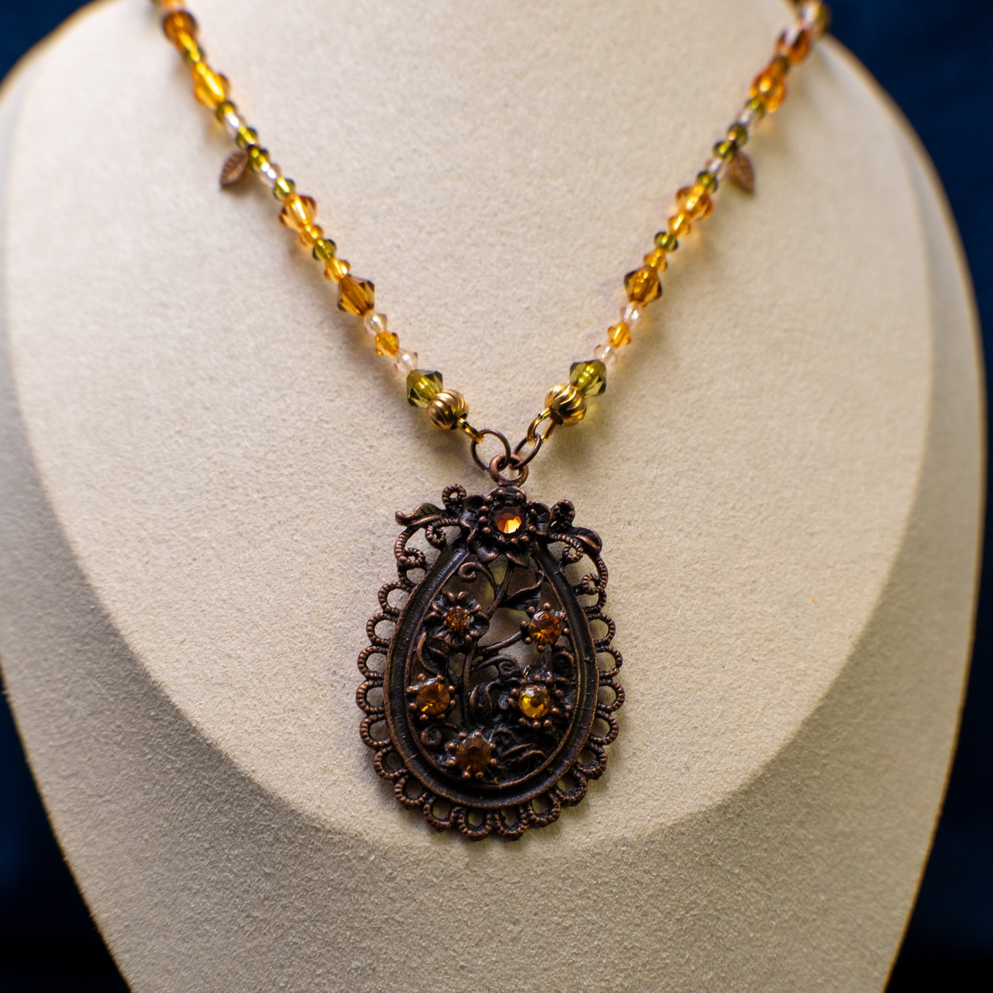 Ketting met antiek koper bloemenornament en amberkleurige facetkralen