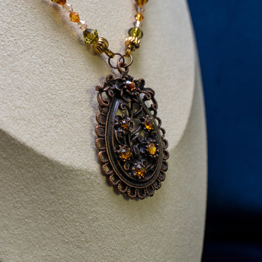 Ketting met antiek koper bloemenornament en amberkleurige facetkralen