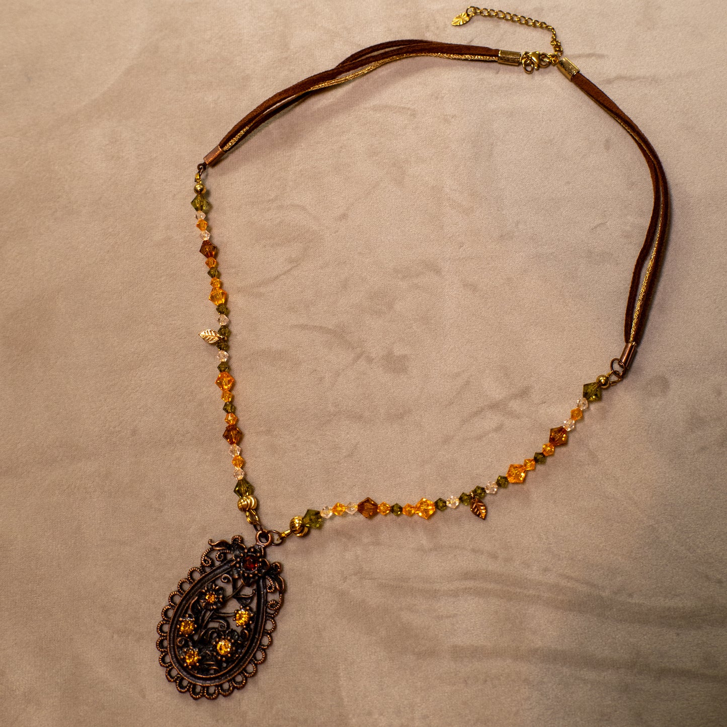 Ketting met antiek koper bloemenornament en amberkleurige facetkralen