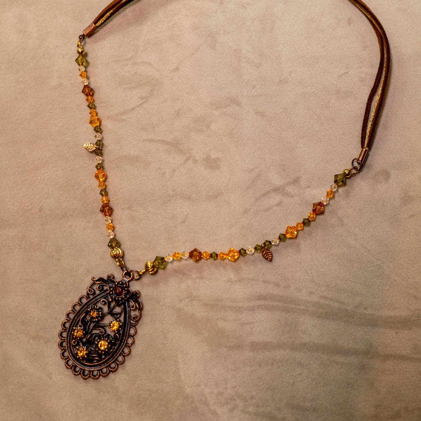 Ketting met antiek koper bloemenornament en amberkleurige facetkralen