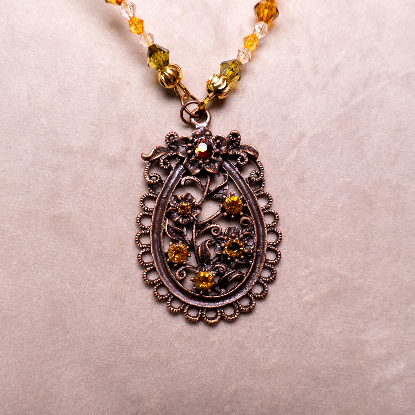 Ketting met antiek koper bloemenornament en amberkleurige facetkralen