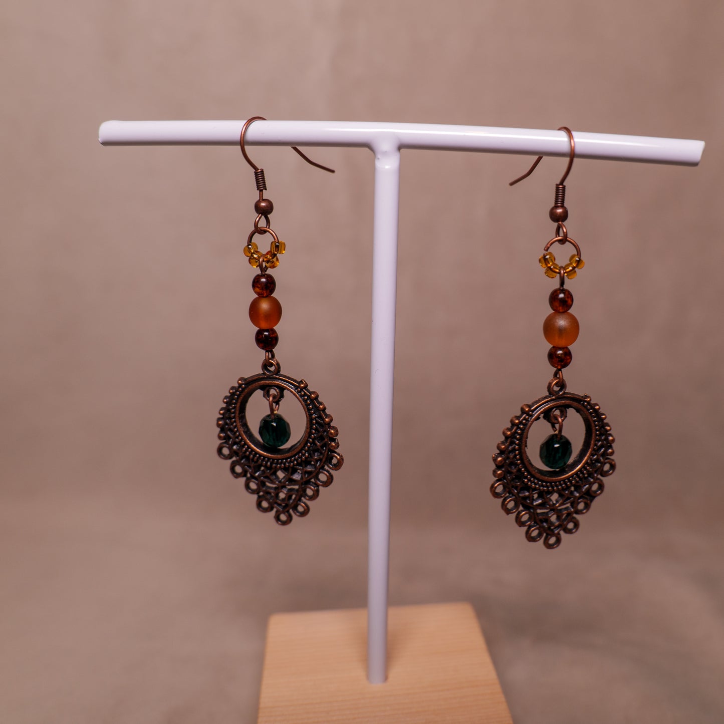Oorbellen met antiek koperkleurig ornament en oranje en groene kralen