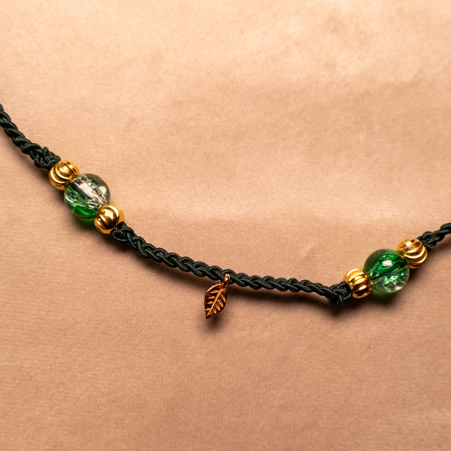 Gevlochten donkergroene armband met gekraakte kralen en goudkleurig blaadje