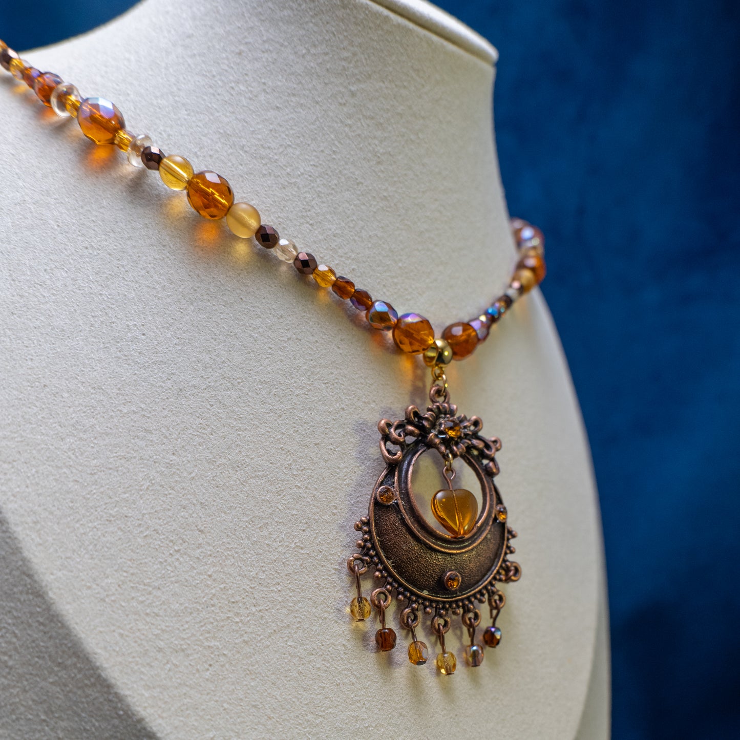 Ketting met antiek koperkleurig rond ornament met hart en amberkleurige facetkralen