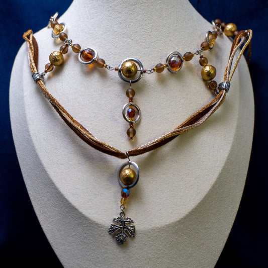 Ketting met blad-hanger, bruin lint en goudkleurige kralen