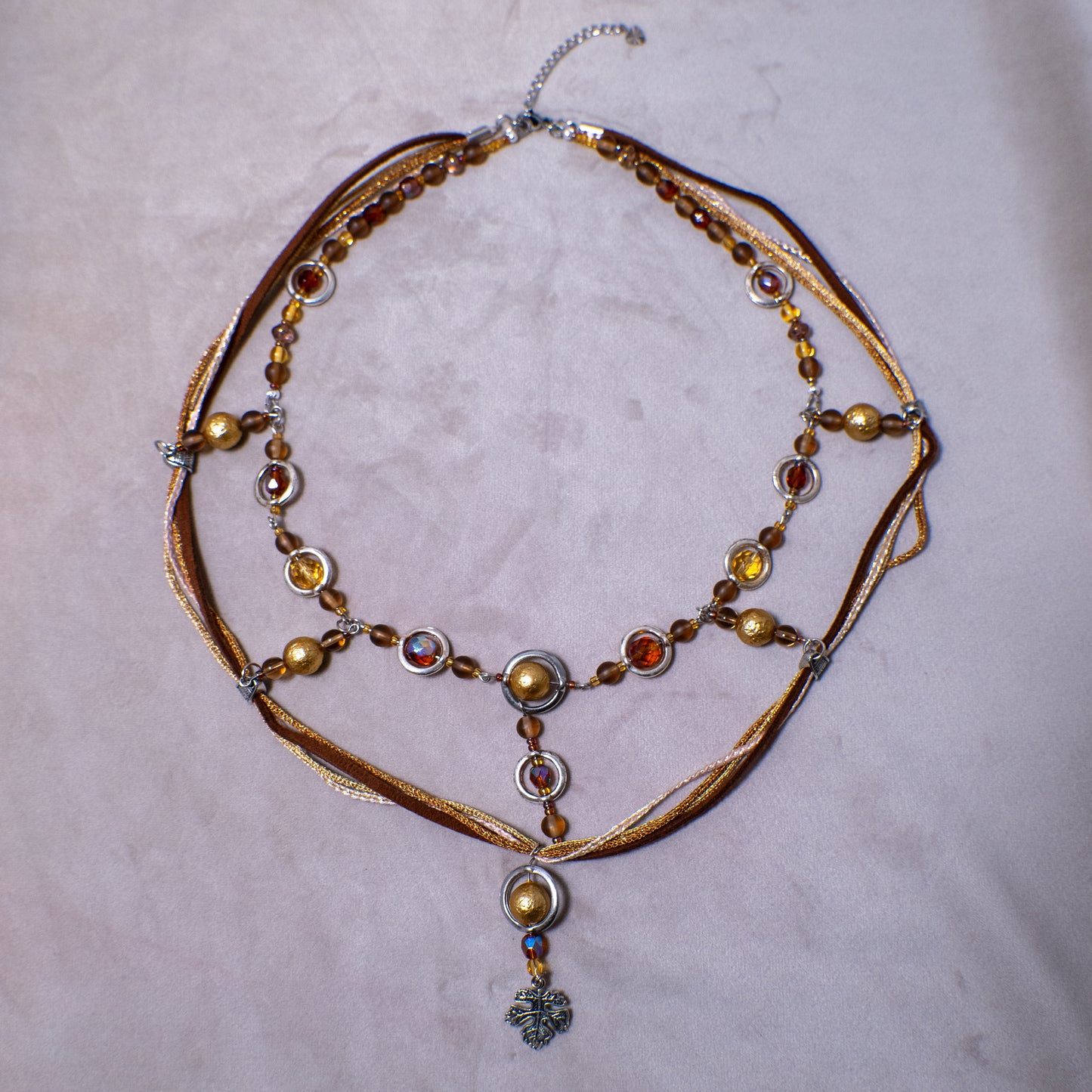 Ketting met blad-hanger, bruin lint en goudkleurige kralen