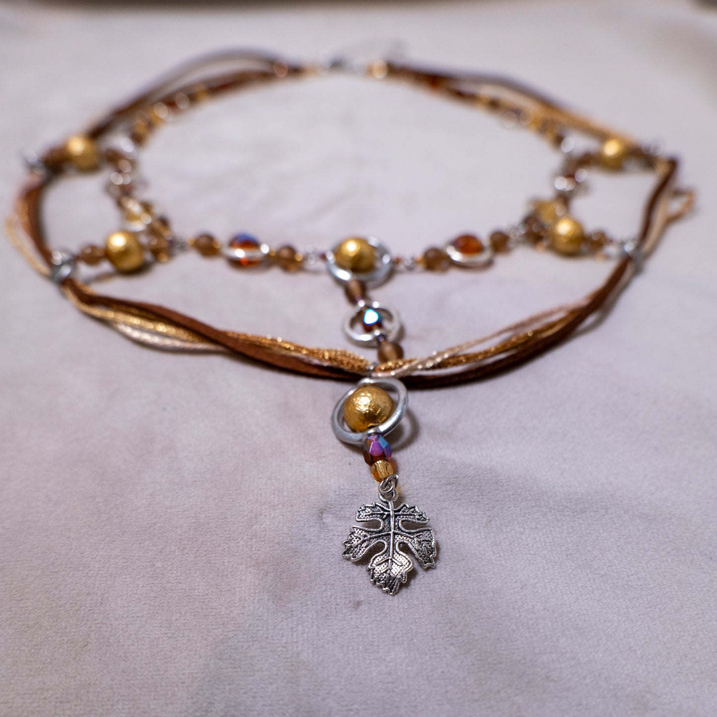 Ketting met blad-hanger, bruin lint en goudkleurige kralen