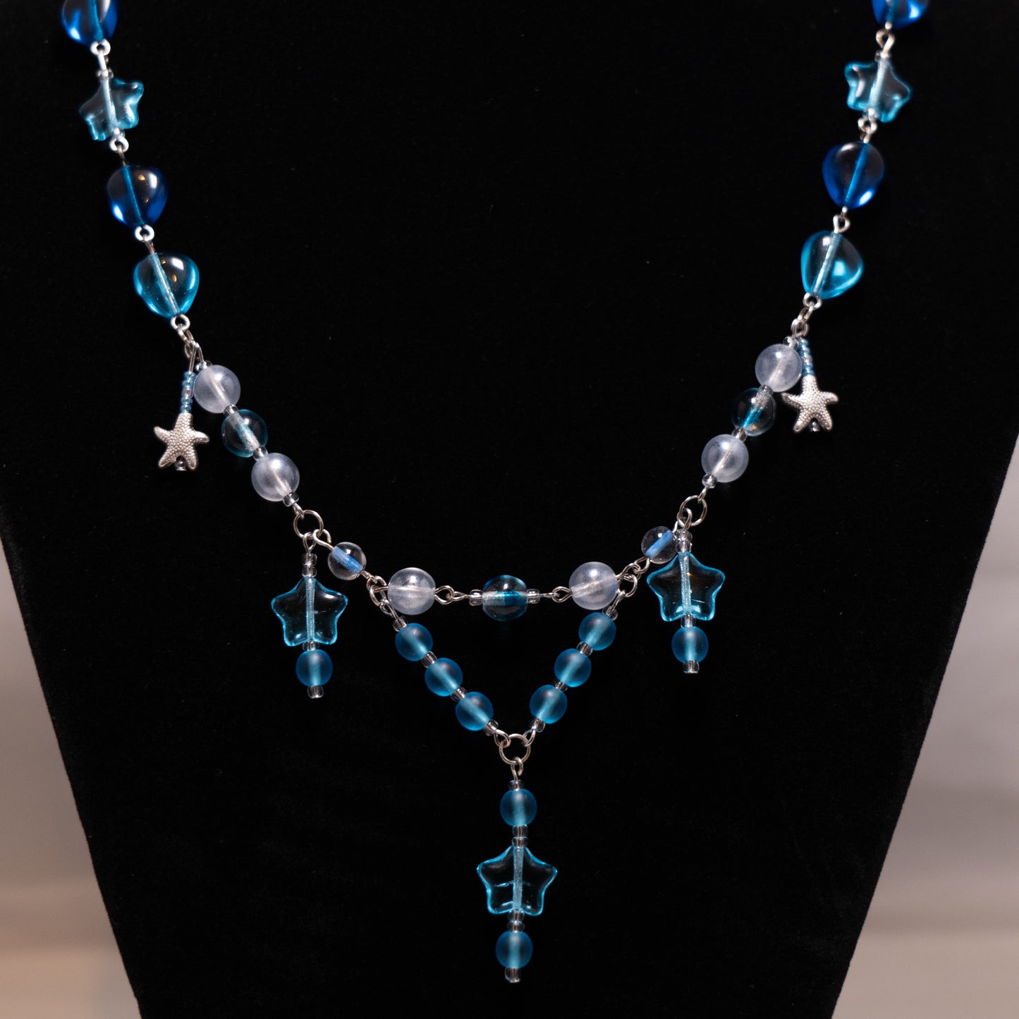 Ketting met blauwe sterren en zeesterren op zwarte achtergrond.