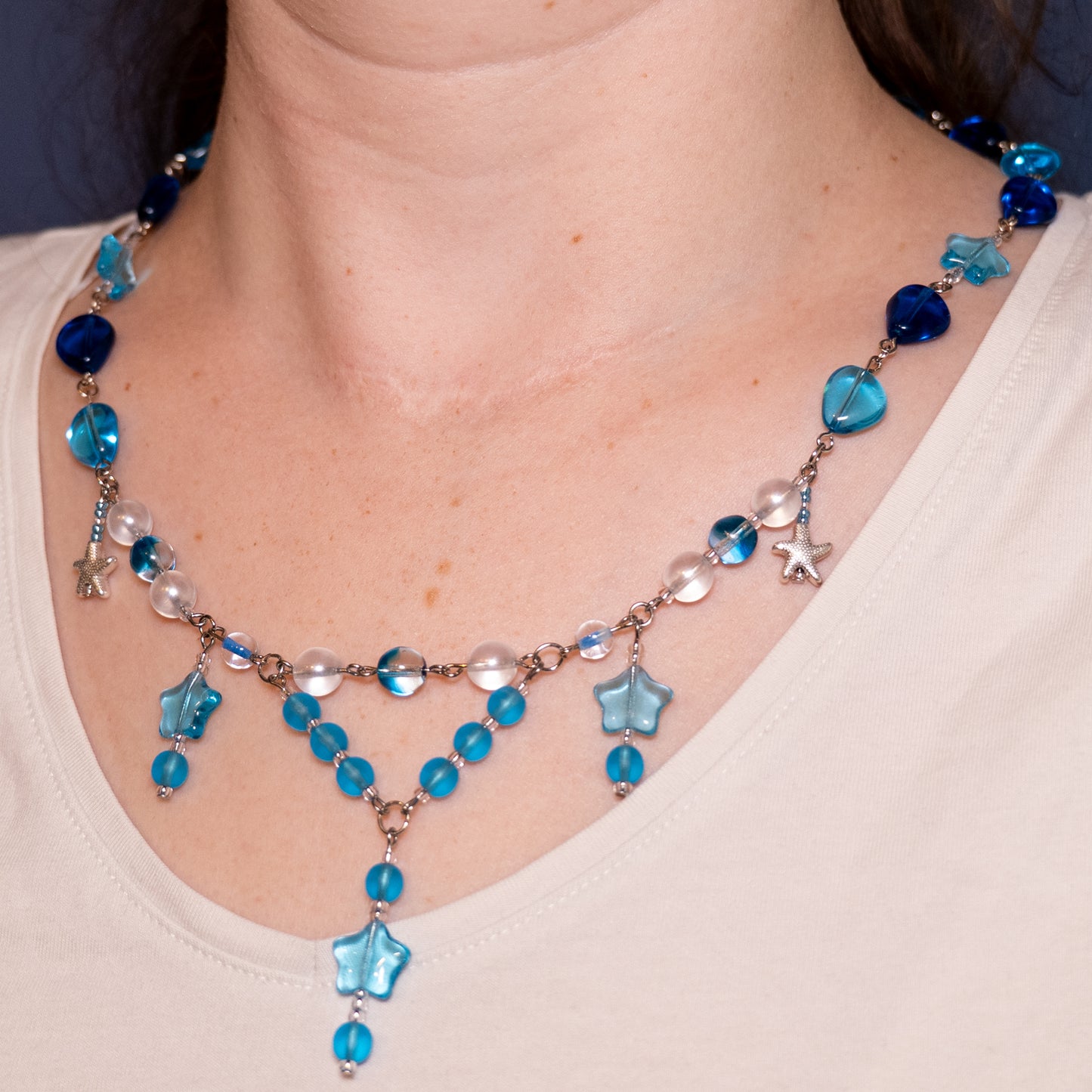 Ketting met blauwe sterren en blauwe glaskralen gedragen om de hals.