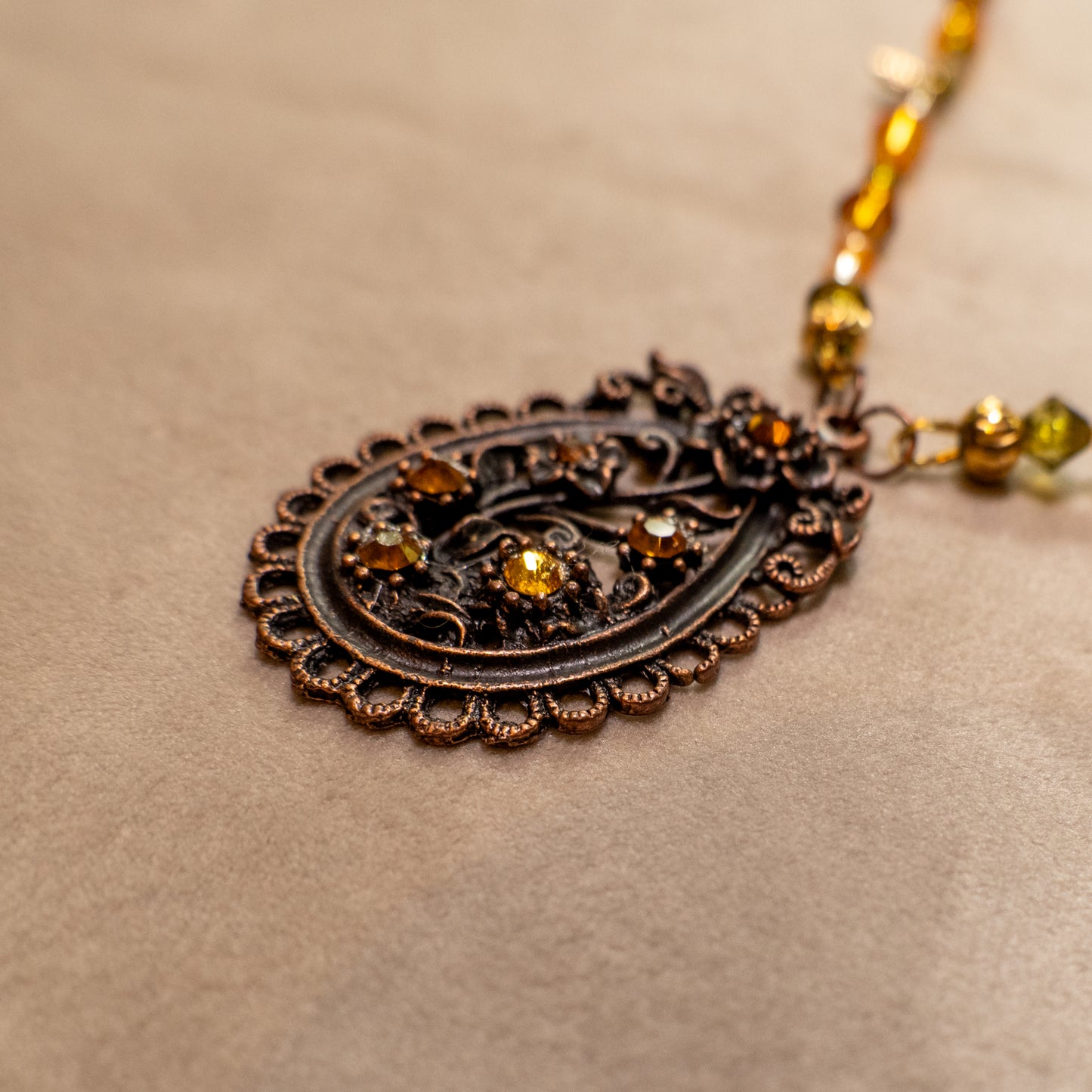 Ketting met antiek koper bloemenornament en amberkleurige facetkralen