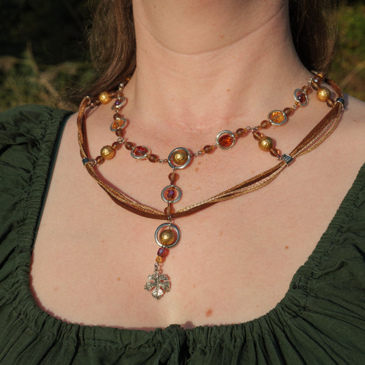 Ketting met blad-hanger, bruin lint en goudkleurige kralen
