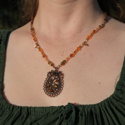 Ketting met antiek koper bloemenornament en amberkleurige facetkralen