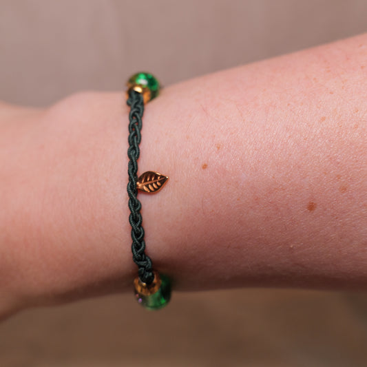 Gevlochten donkergroene armband met gekraakte kralen en goudkleurig blaadje