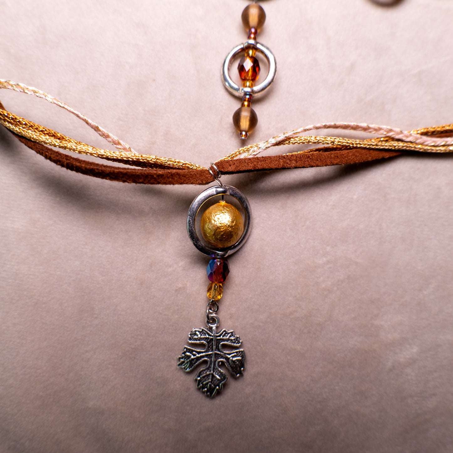 Ketting met blad-hanger, bruin lint en goudkleurige kralen