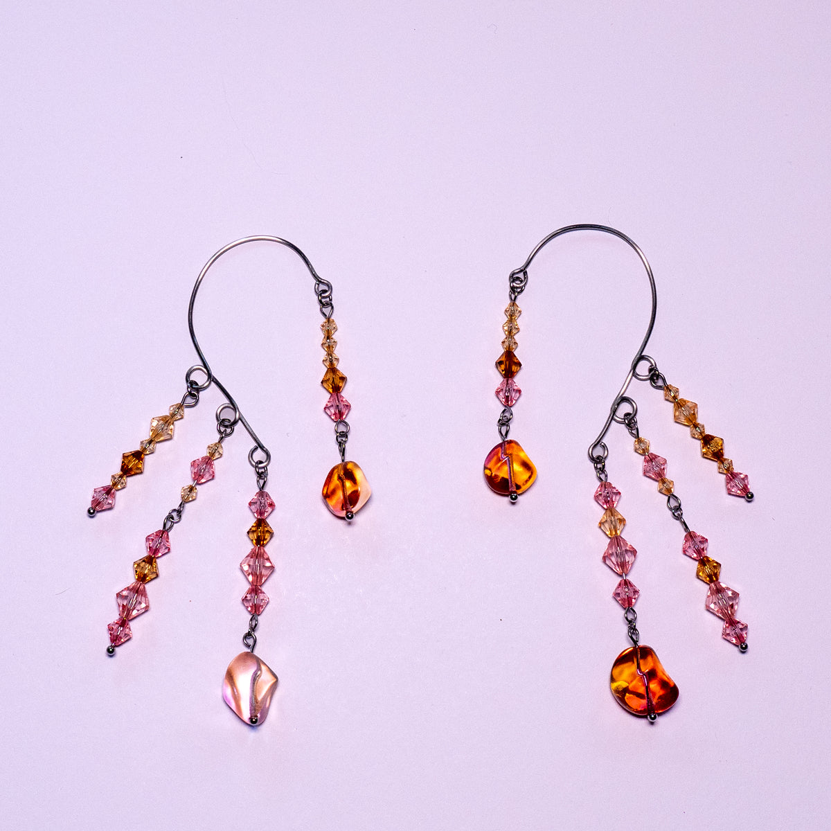 Ear cuffs herfstzon op een witte achtergrond. Met oranje en roze kralen.