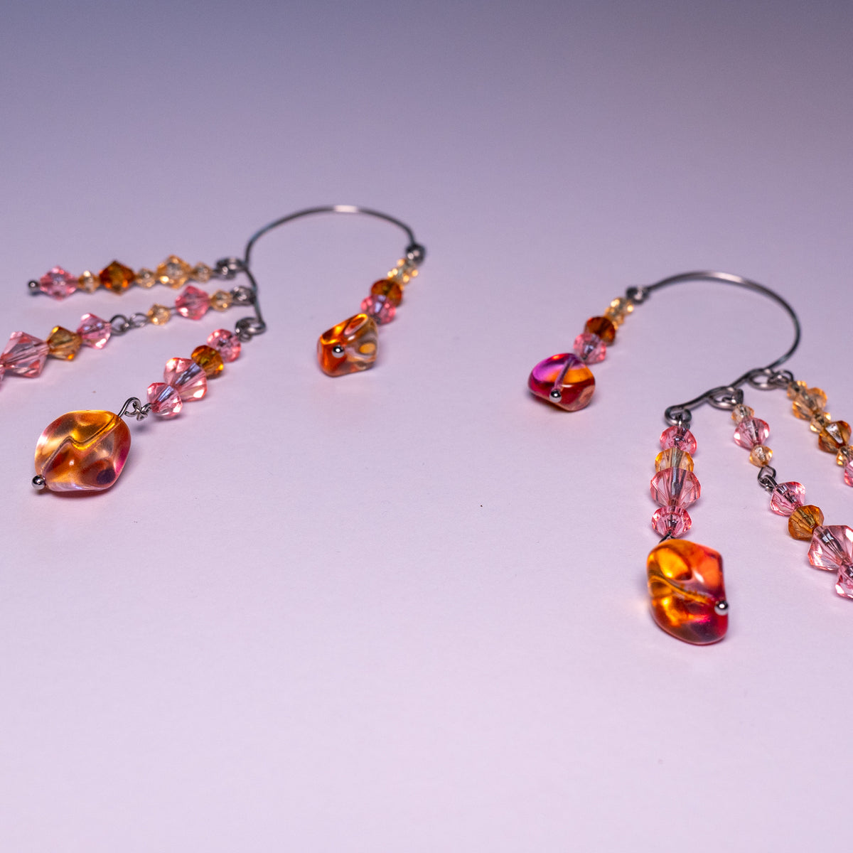 Ear cuffs herfstzon op een witte achtergrond. Met oranje en roze kralen.