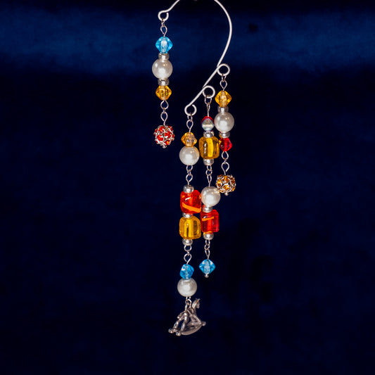 Ear cuff speelgoedkist met hobbelpaard op donkerblauwe achtergrond.