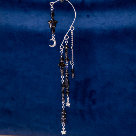 Zwart met zilver ear cuffs met maantjes en sterretjes op een blauwe achtergrond.