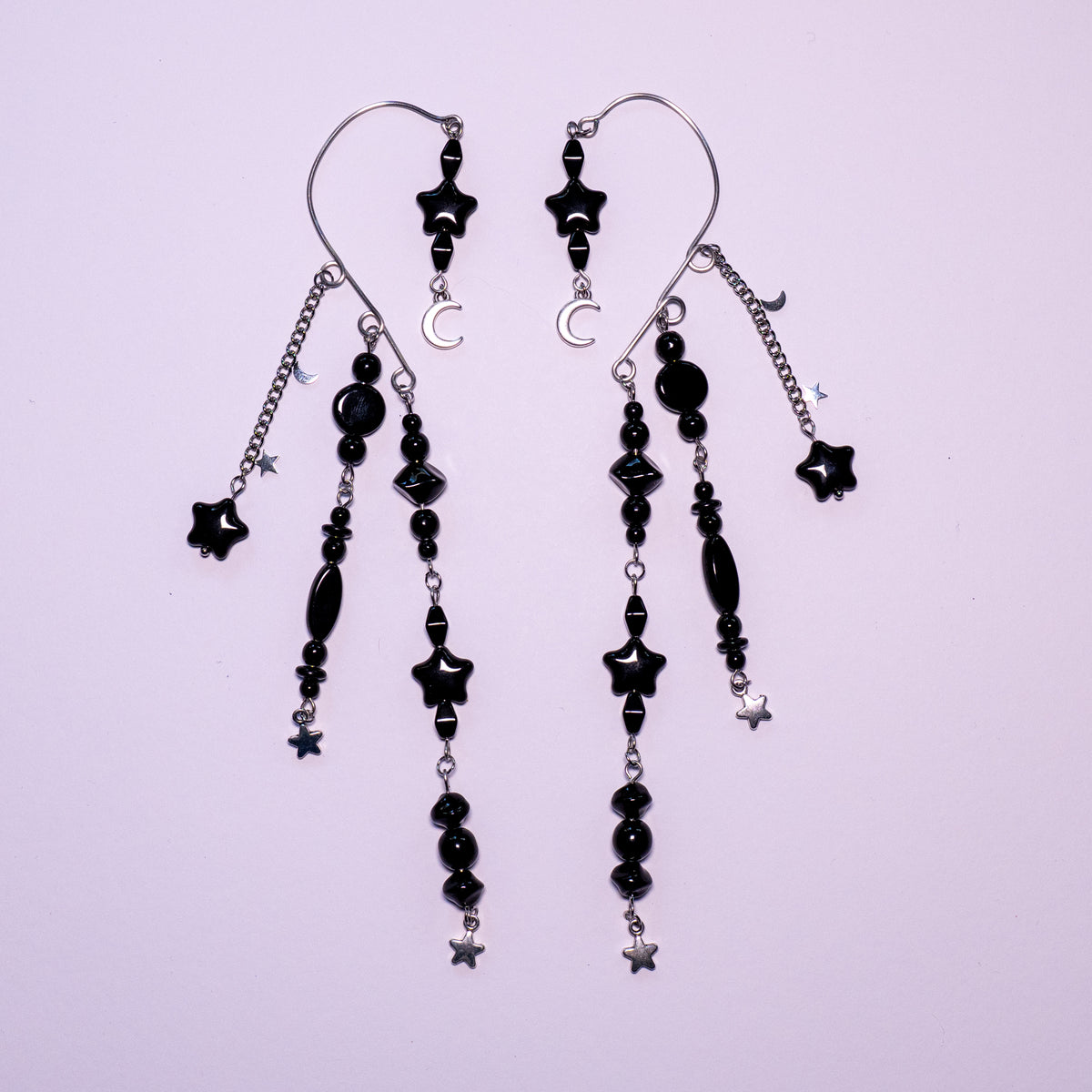 Zwart met zilver ear cuffs met maantjes en sterretjes op een witte achtergrond.