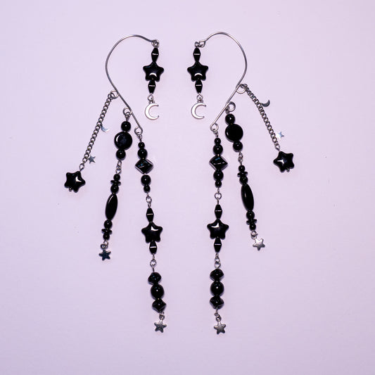 Zwart met zilver ear cuffs met maantjes en sterretjes op een witte achtergrond.